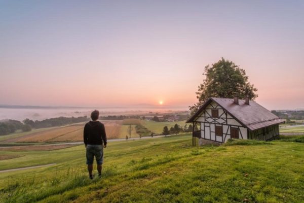 Man watching sunrise on a green field